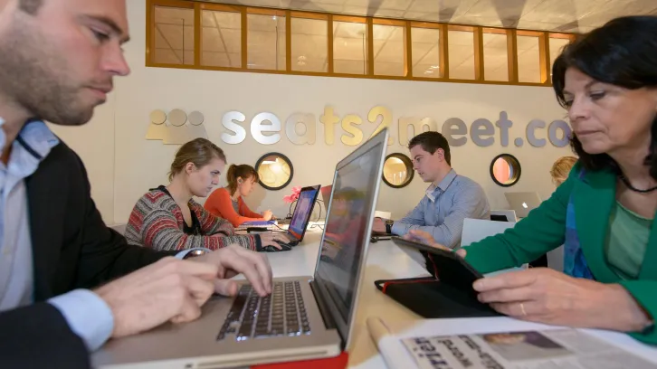 Man achter laptop aan tafel met andere mensen